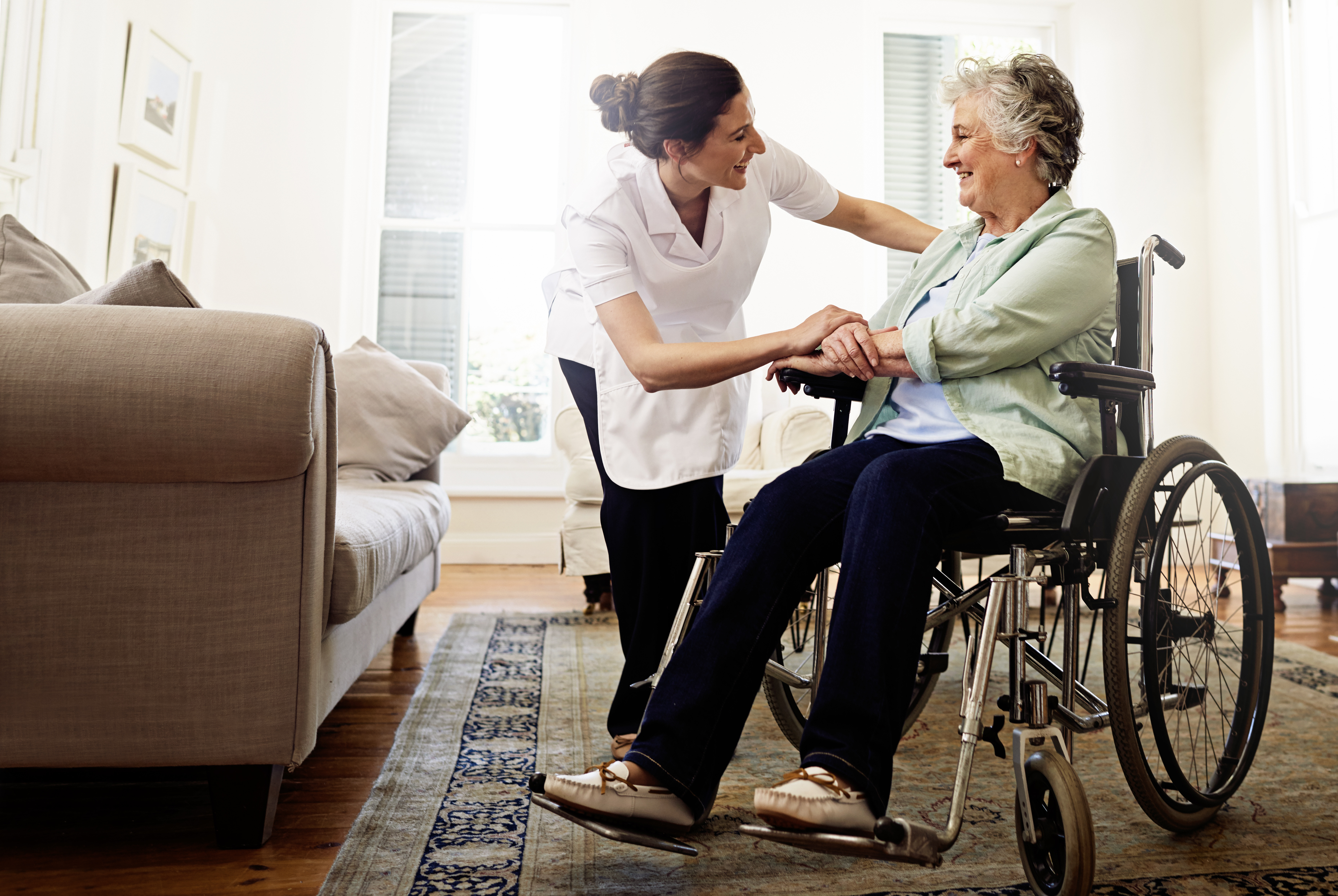Shot of a smiling caregiver helping a senior woman in a wheelchair at home